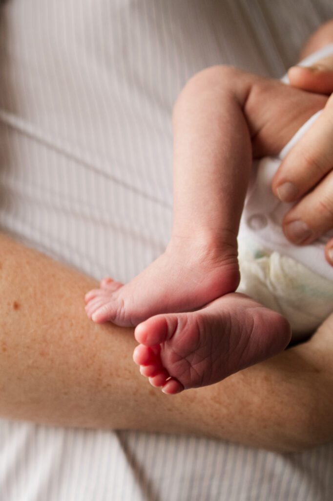 Close up image of a newborn babies little wrinkled feet as he is held by his da.