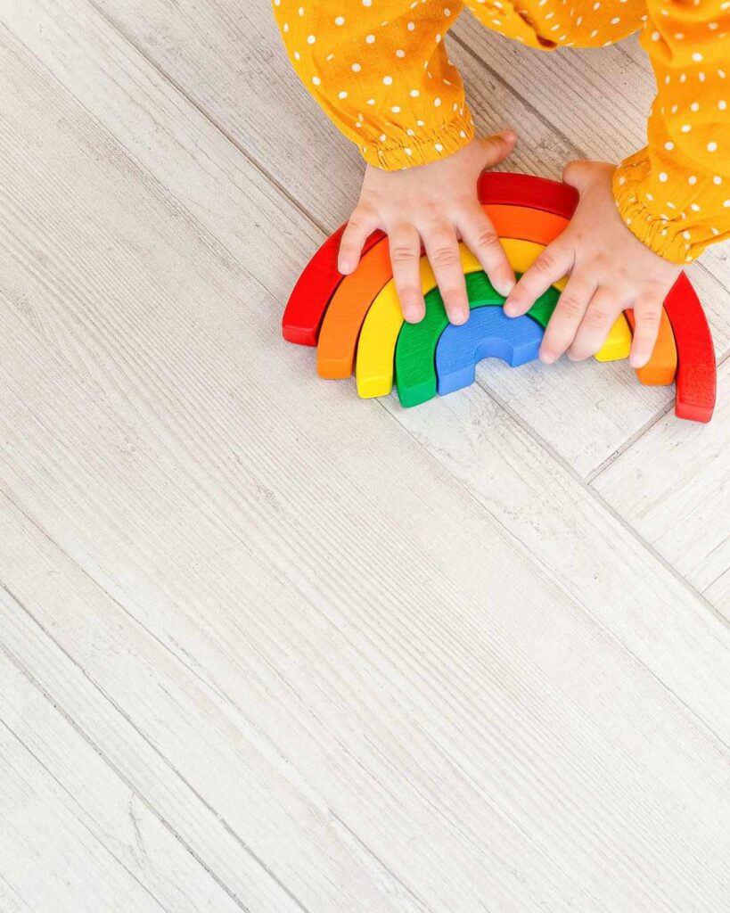 Baby plays with wooden colourful rainbow on floor