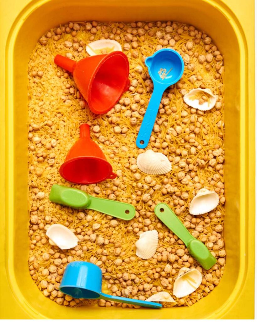 Sensory tray filled with pasta chickpeas, shells and scoops