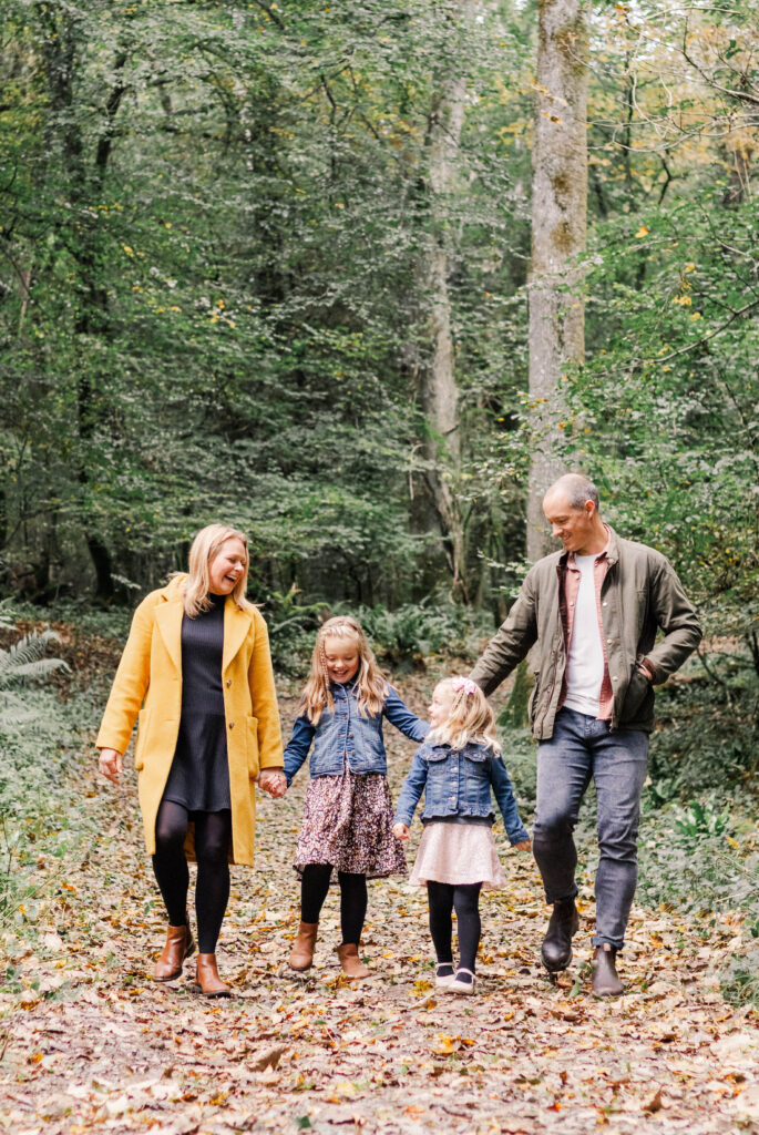 Family walks through the woods laughing together for a family photography session