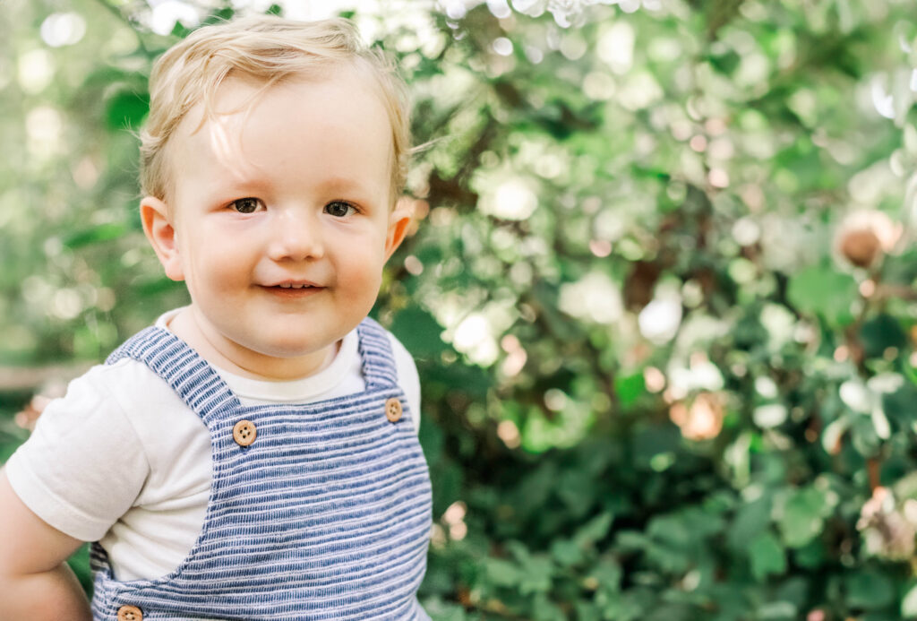 Toddler stands in front of dappled son for his picture
