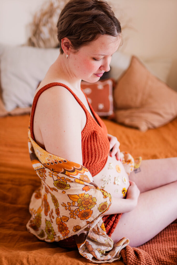 Pregnant lady looks down at her baby bump wrapped in vintage fabric