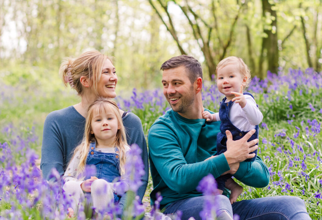 A young family laugh together as they enjoy a bluebell photoshoot at Sparkford Wood