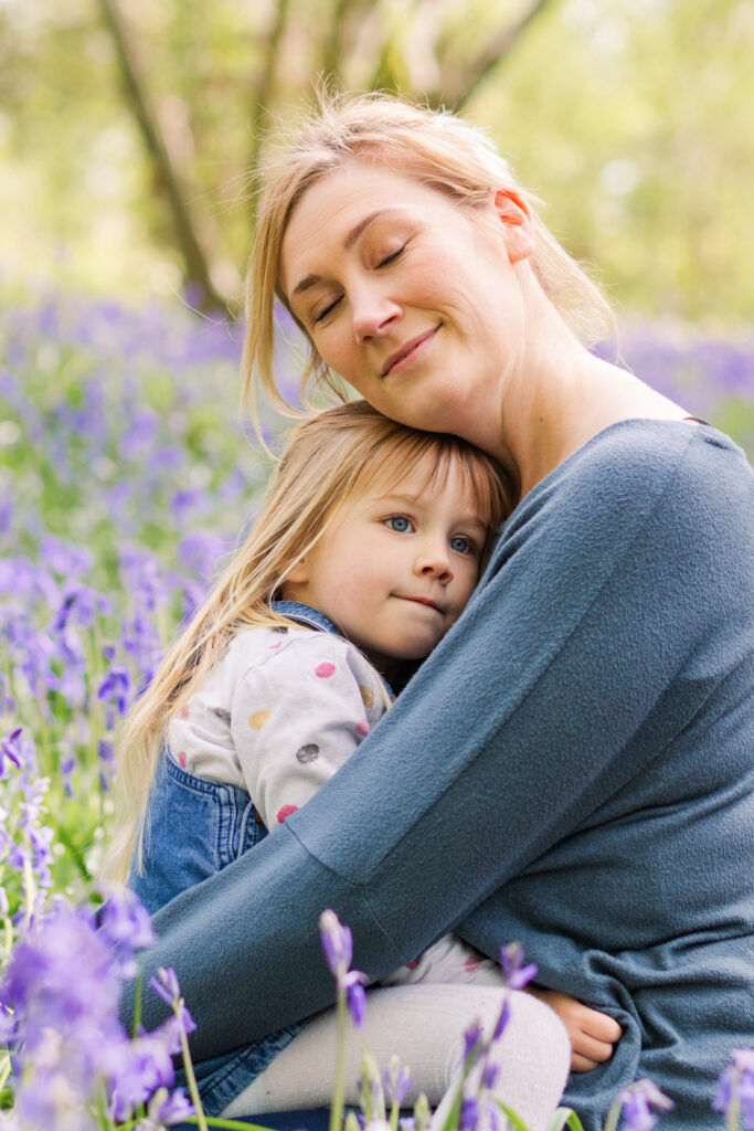 Mum closes her eyes as her and her daughter share a cuddle among the purple flowers