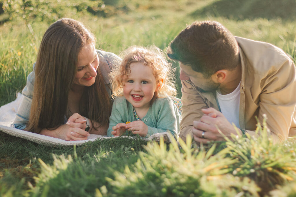 Family lay together in the Golden Hour light at Ham Hill Park, Somerset