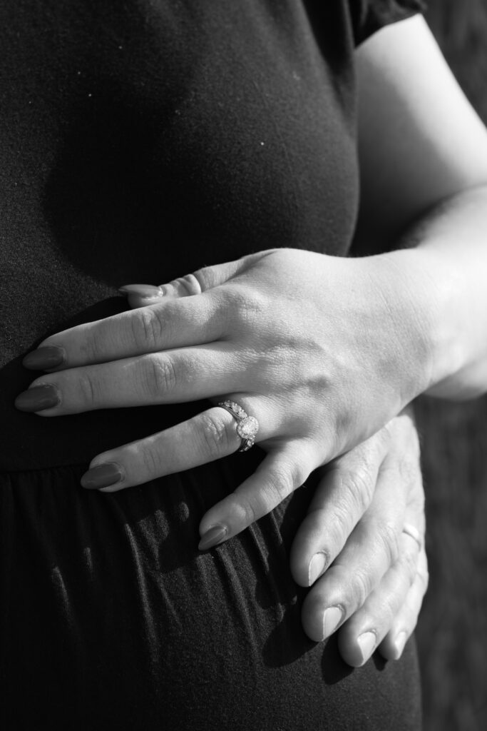 Two hands  of mother and father rest gently on a baby bump