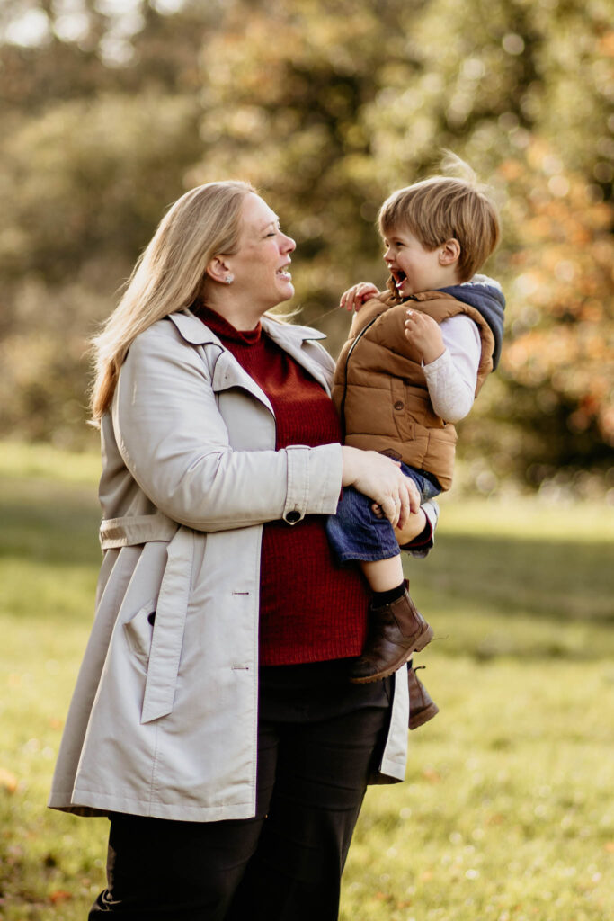 little boy laughs at his my as she holds him in her arms