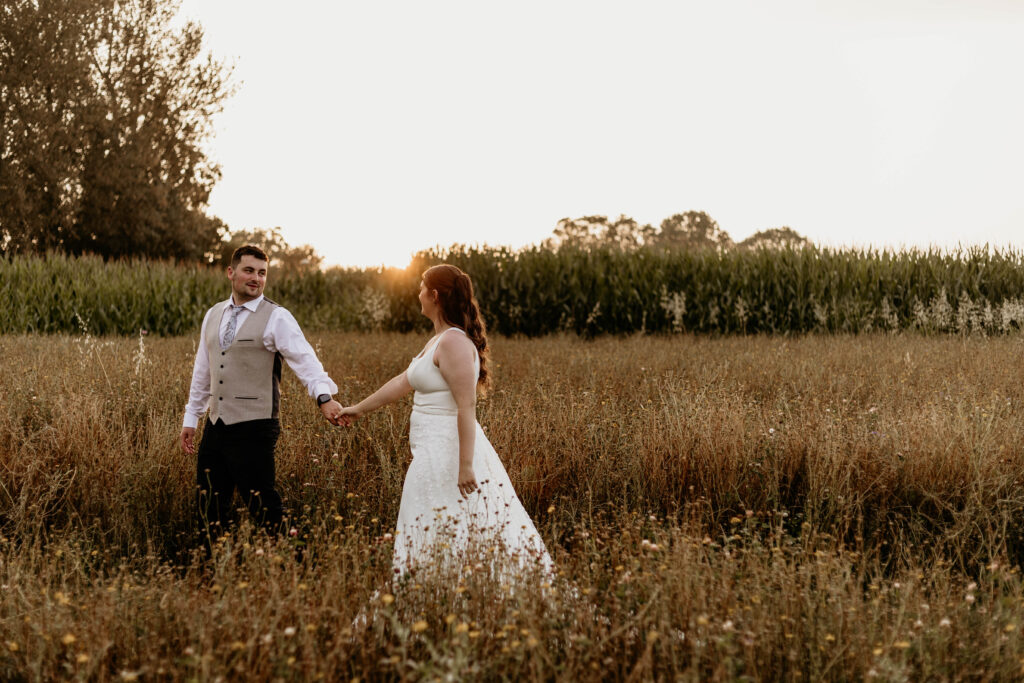 Couple walk together amongst the wild flowers during their Spring Wedding