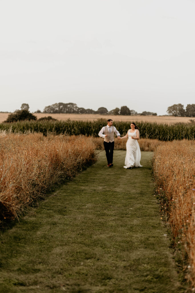 Bride and groom run through a flower meadow