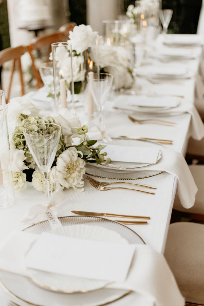 Wedding breakfast table laid with elegant setting and floral centre pieces