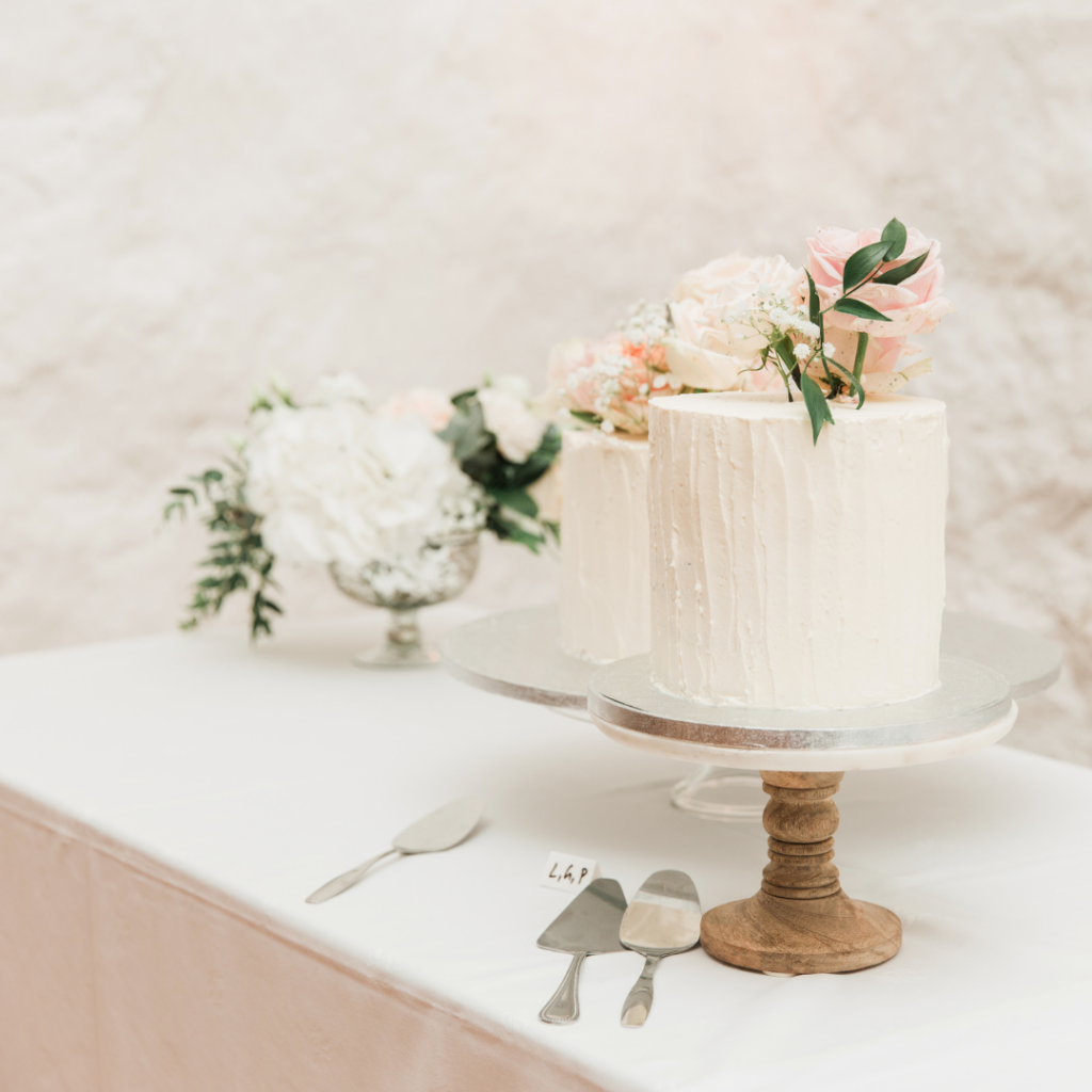 Spring wedding cake featuring fresh flowers sits on a table next to flowers and cake knife