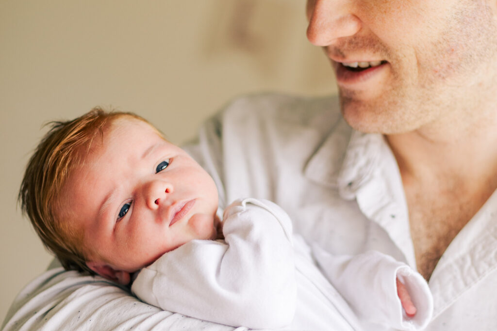 Newborn lays relaxed in fathers arms