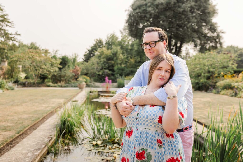 Couple stand in front of ornamental pond at Tintinhull Garden, Somerset