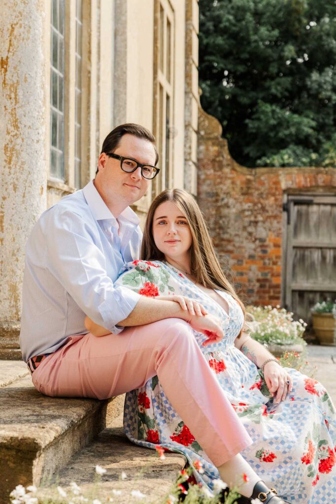 Engaged couple sit on the steps of Tintinhull House during their pre wedding photoshoot