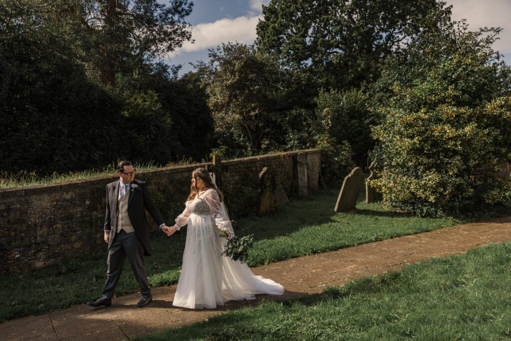 Just married couple walk down the church path hand in hand