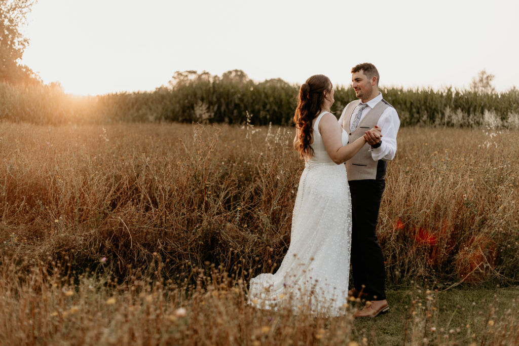 Newlyweds dance slow dance in a flower field in Somerset as the sun sets on their wedding day