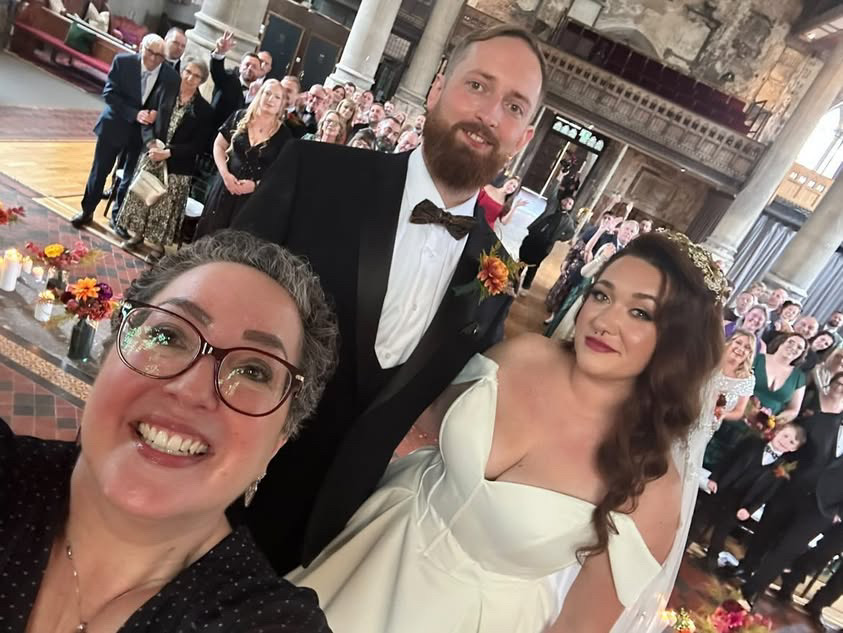 Wedding celebrant takes selfie of bride groom and wedding guests during ceremony